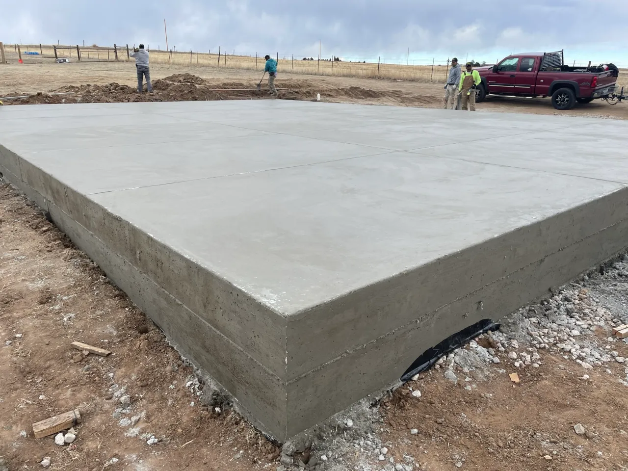 Thick new construction concrete foundation slab with crew working in El Paso County, CO