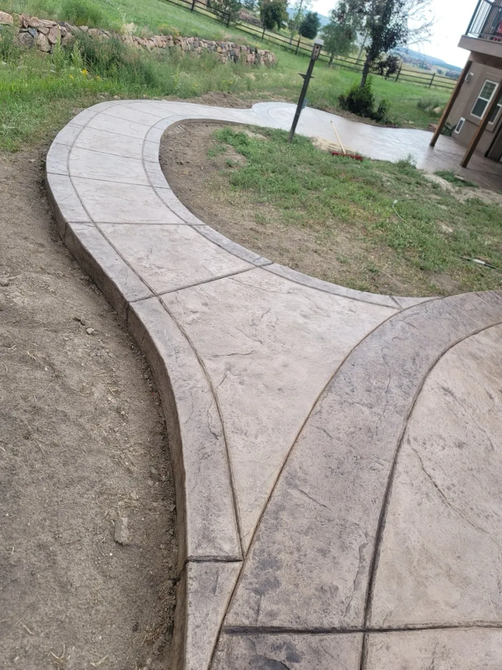 Curved stamped concrete walkway with ashlar slate pattern leading to a patio in El Paso County, CO