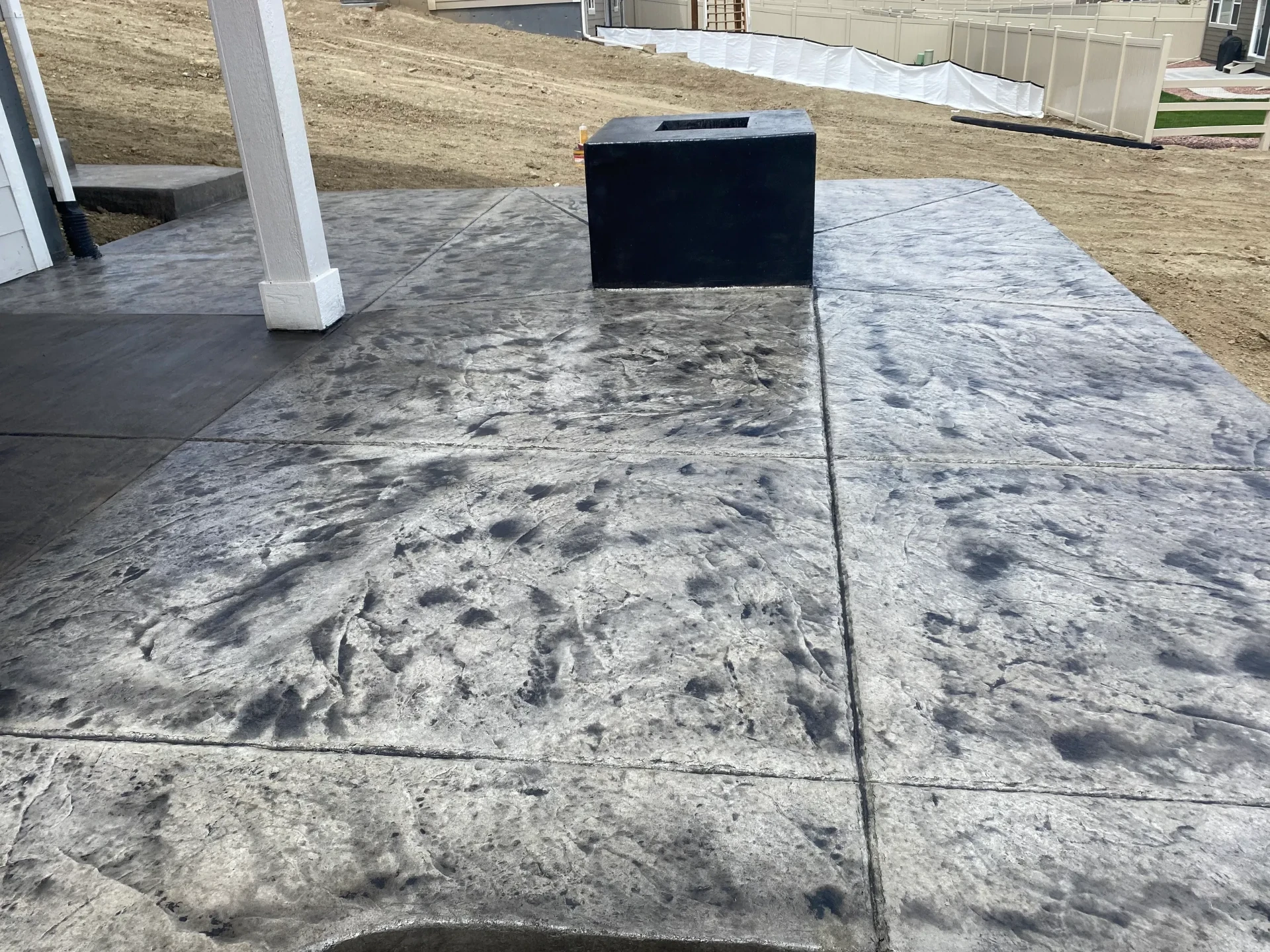 Charcoal gray stamped concrete patio with a black concrete fire pit in Colorado Springs, CO