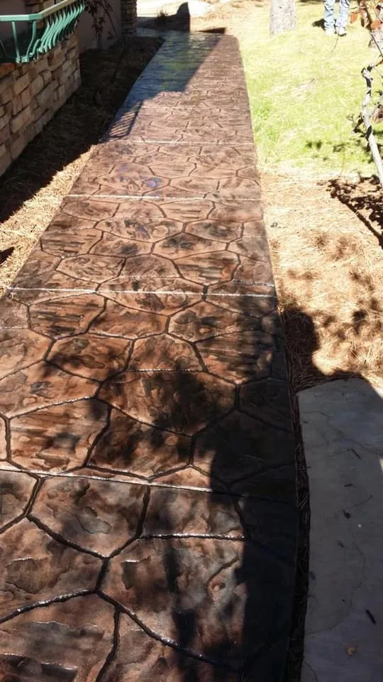 Rich brown stained stamped concrete sidewalk with random stone pattern in Calhan, CO