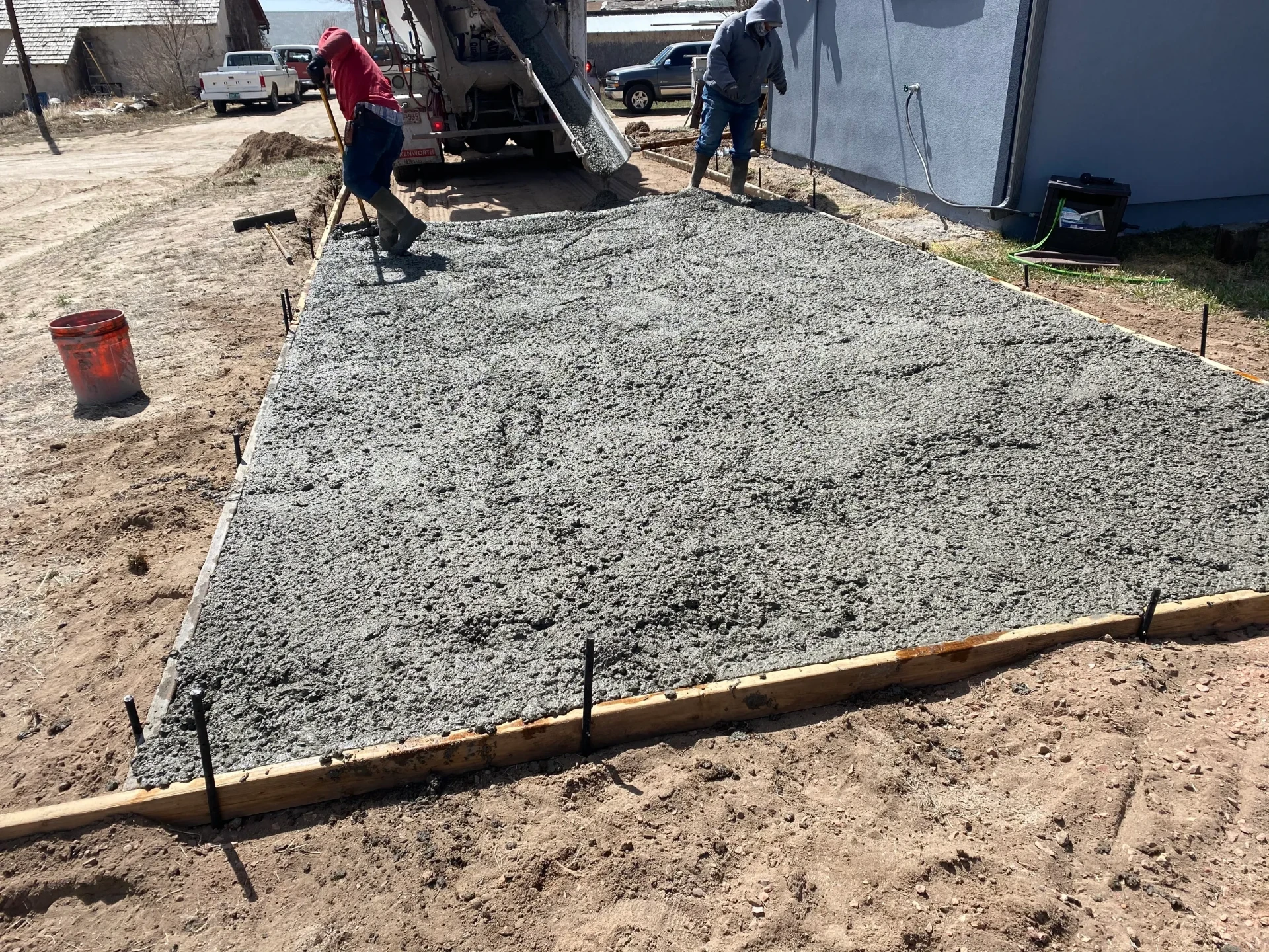 Concrete truck pouring a formed patio slab with crew screeding in Calhan, CO