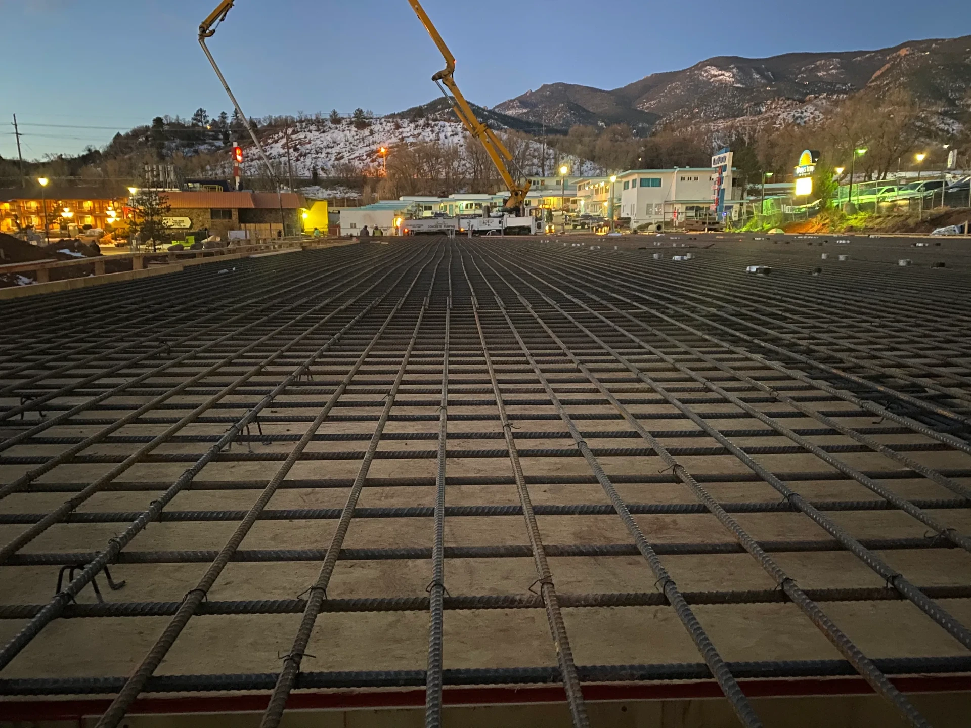 Rebar-tied commercial concrete slab ready for a boom pump pour with the Front Range at sunrise