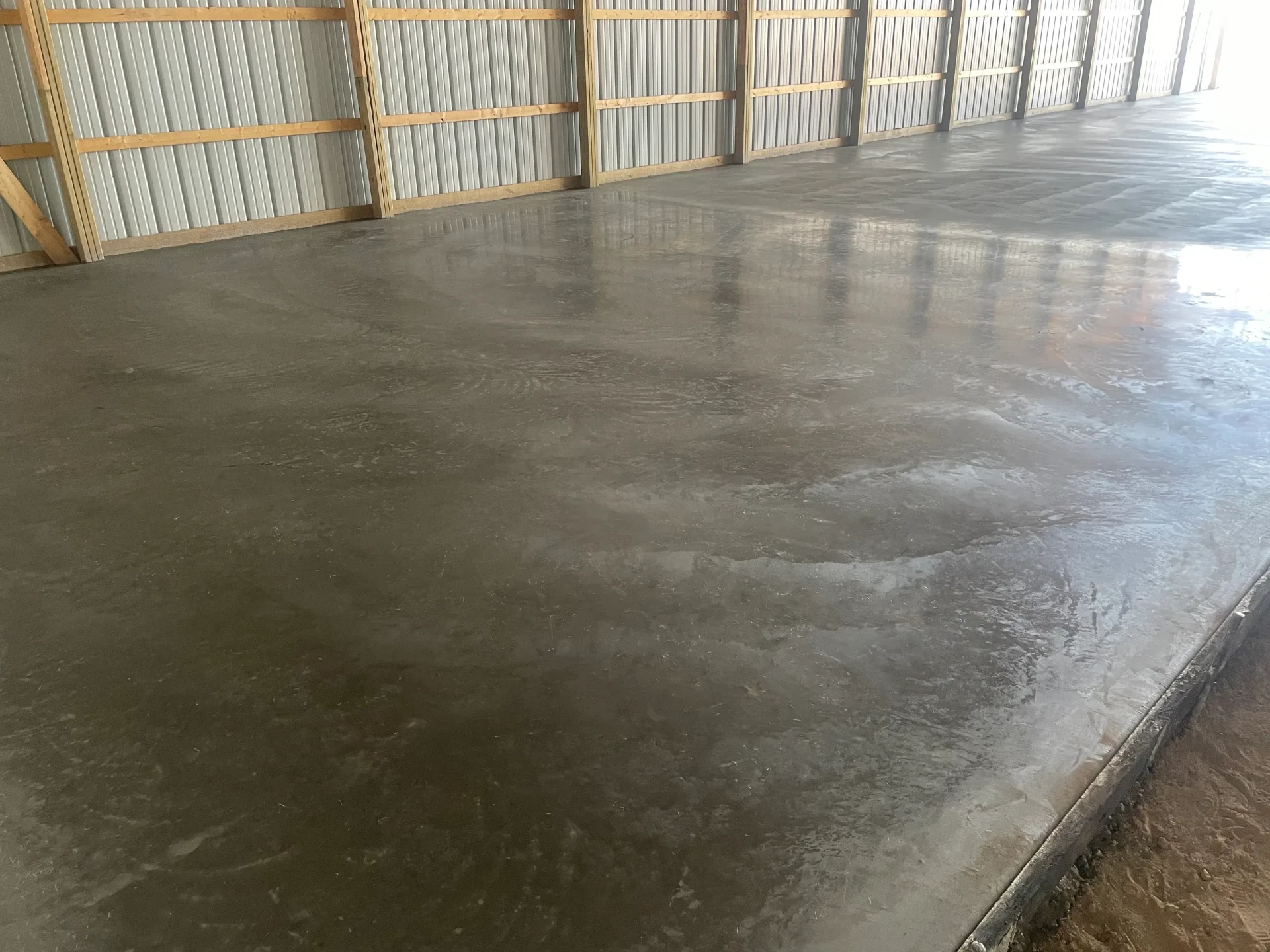 Freshly power-troweled interior concrete floor inside a steel pole barn in El Paso County, CO