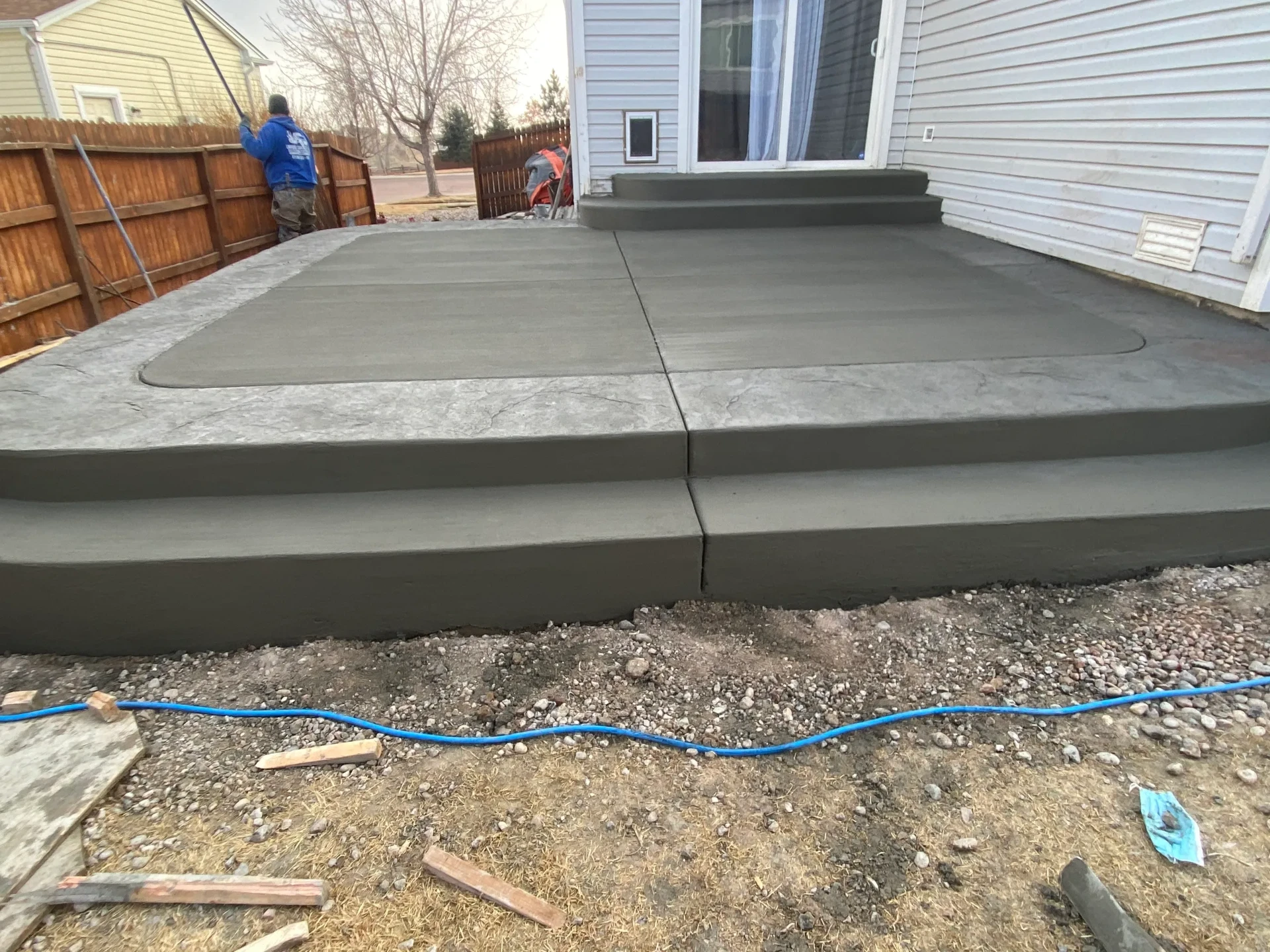 Finished backyard concrete patio with stamped edge banding and steps to a sliding door in Falcon, CO