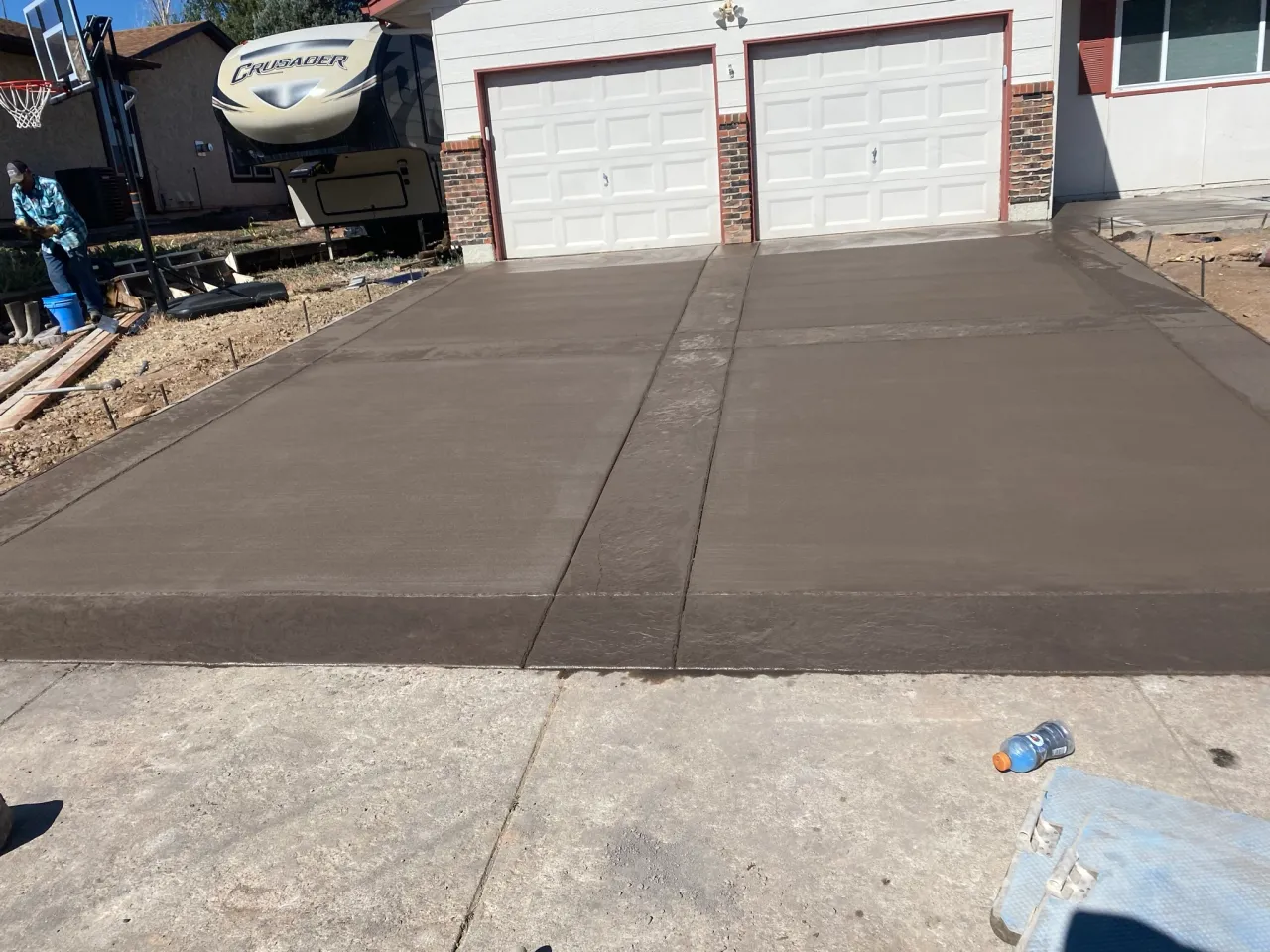 New brown broom-finished concrete driveway in front of a two-car garage in Colorado Springs, CO