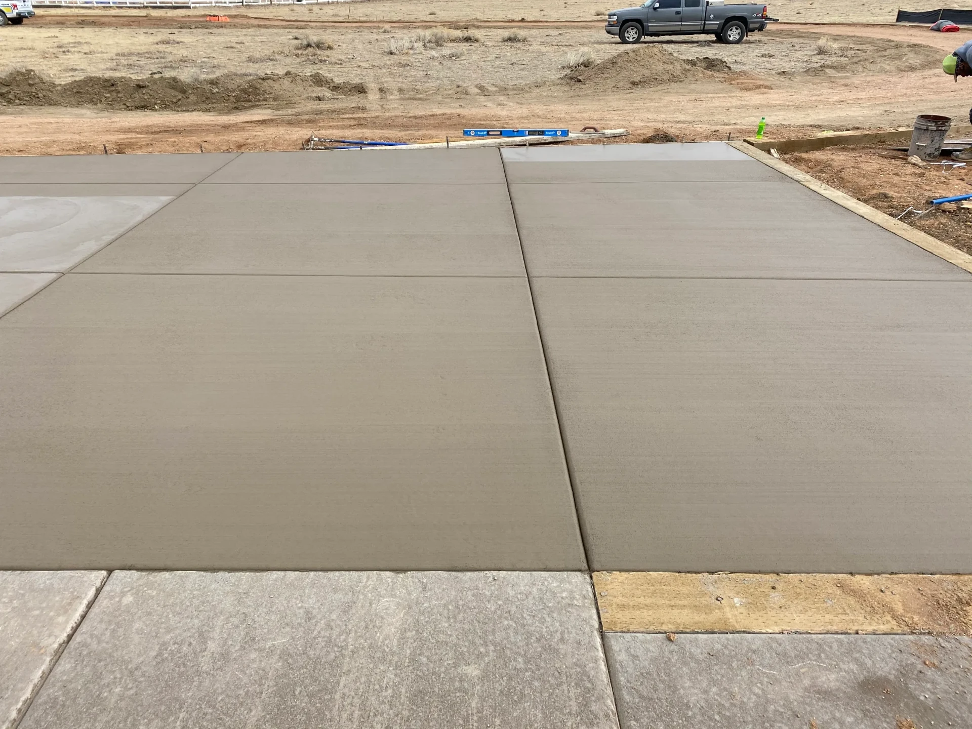 Wide new concrete garage slab with clean control joints on a rural build site in El Paso County, CO