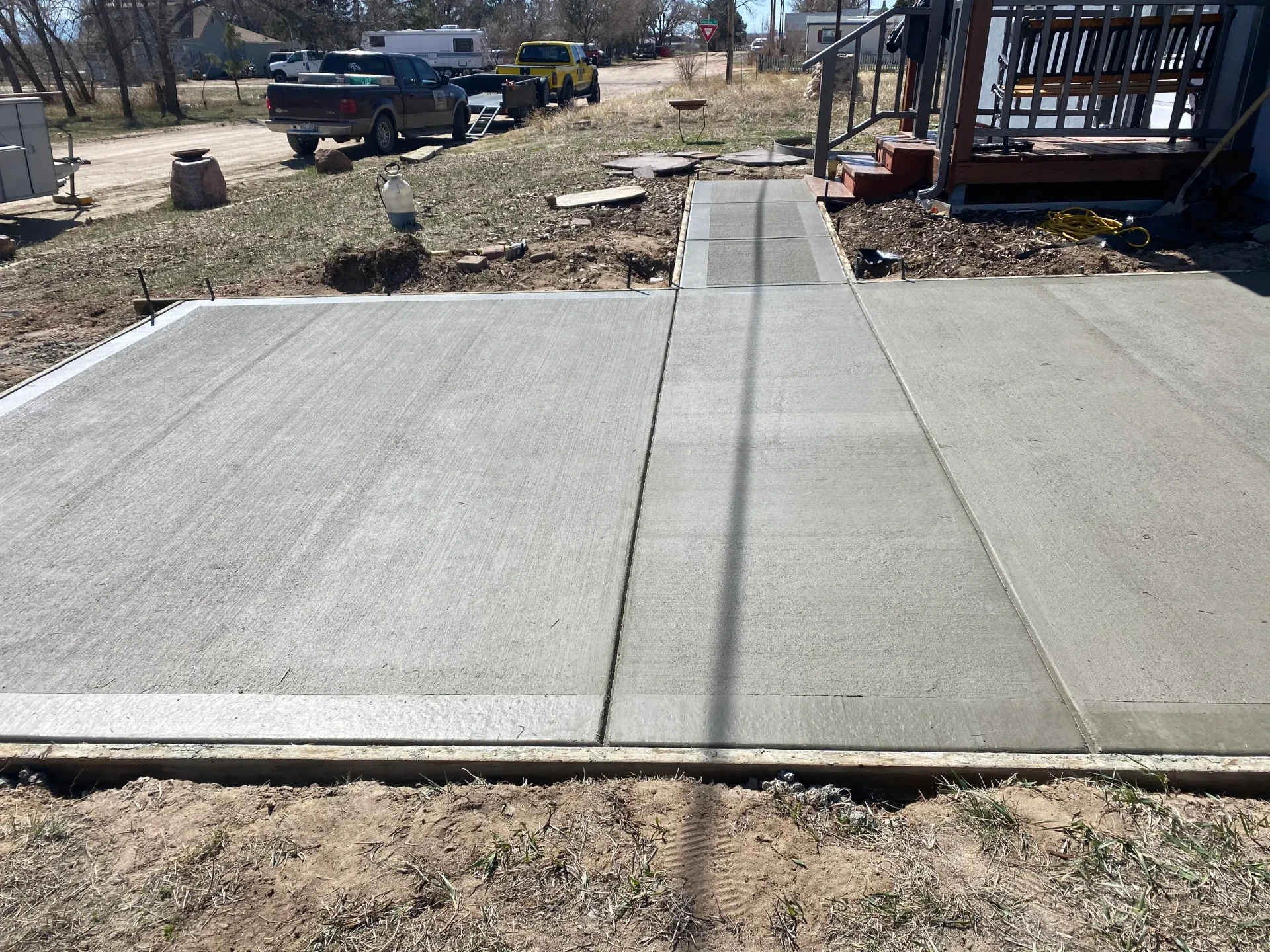 Finished broom-finish concrete patio and connecting walkway to a home deck in Yoder, CO