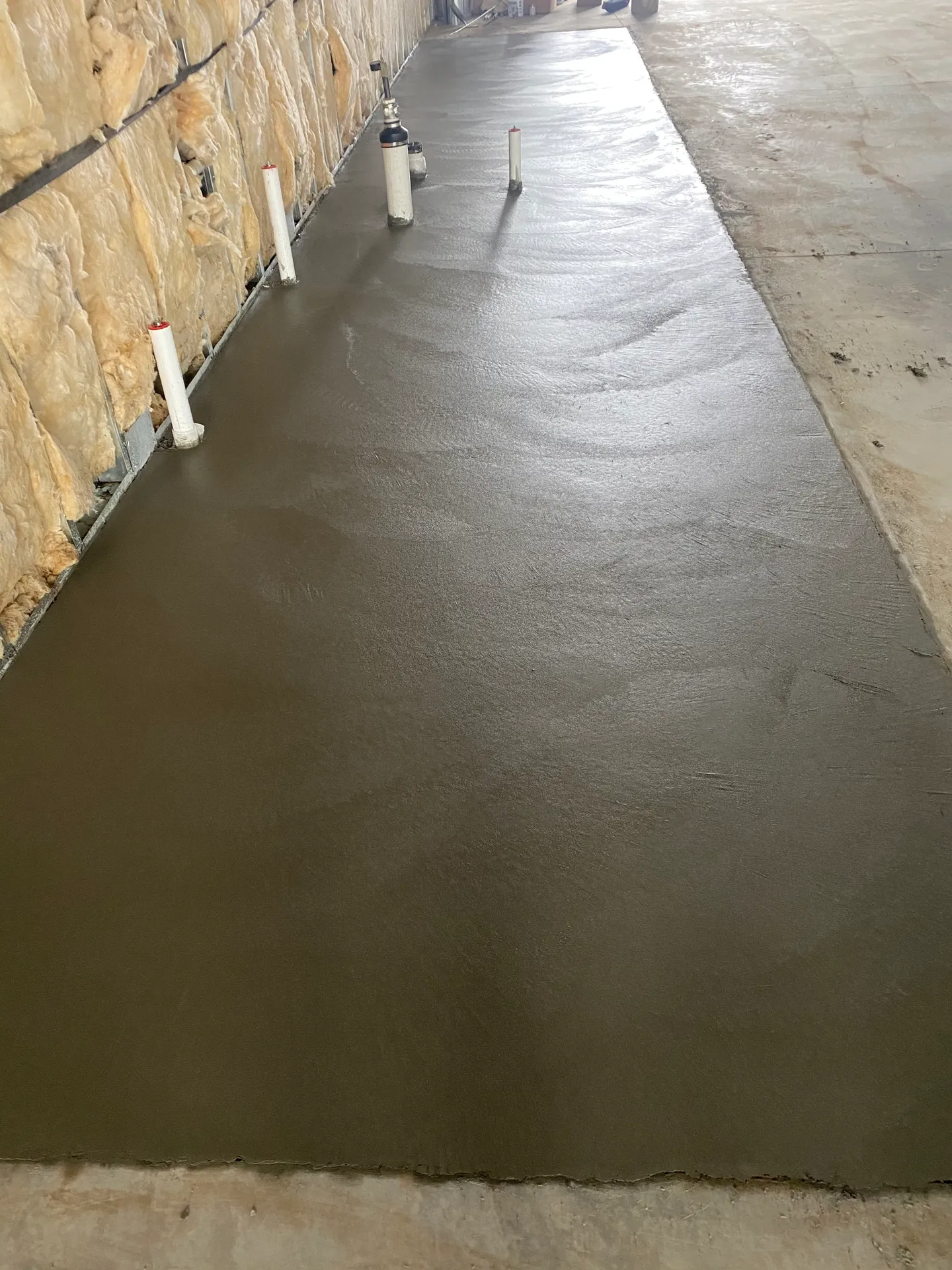 Freshly troweled interior concrete floor with plumbing stub-outs in a Calhan, CO shop building