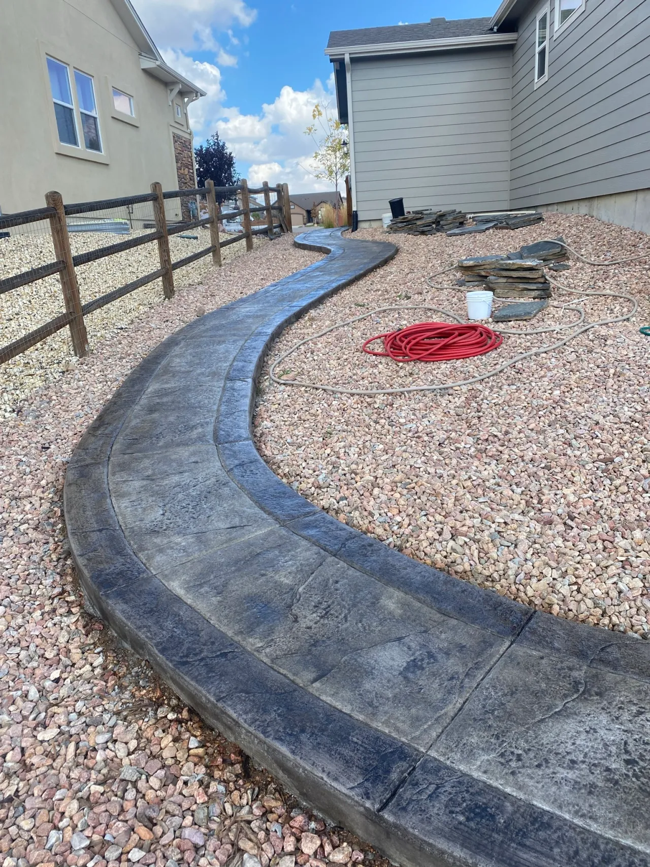 Winding stamped concrete sidewalk through rock landscaping in Falcon, CO