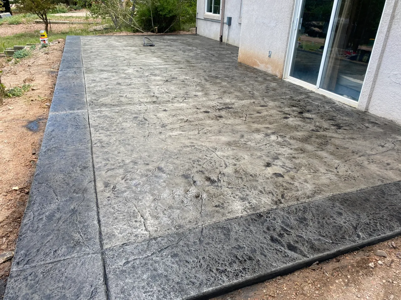 Gray stamped concrete patio with dark charcoal border beside a home in Colorado Springs, CO