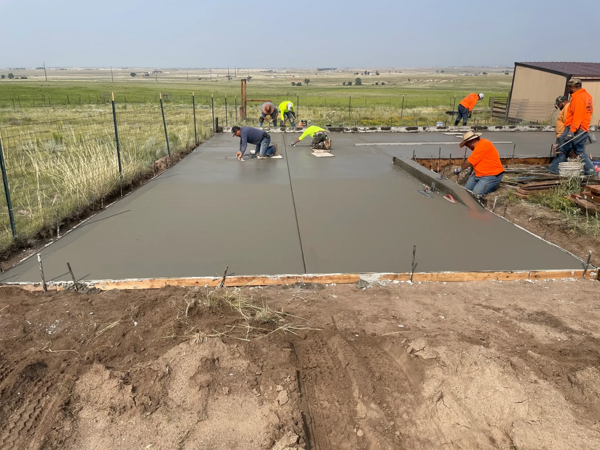 Rango Concrete crew hand-finishing a large residential concrete slab on the Colorado plains